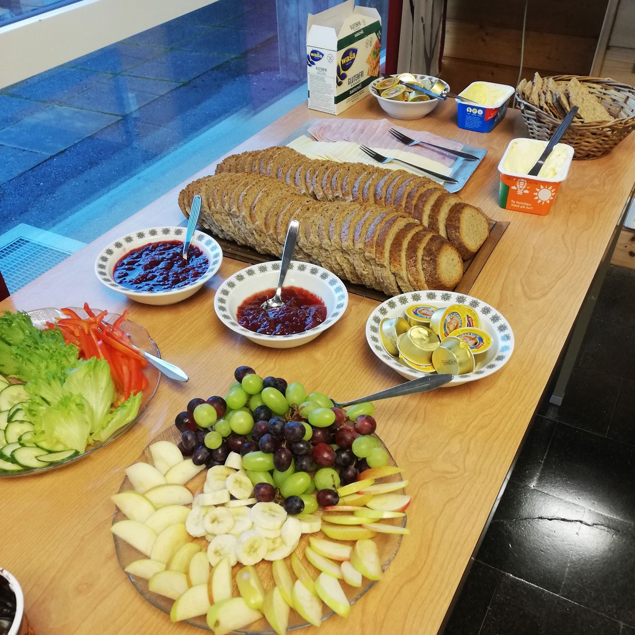 Bilde av bord med brødskiver, pålegg og frukt