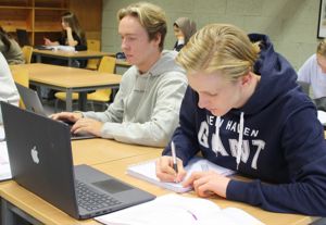 Bildet viser elevar som sit i klasserom og jobbar på PC.